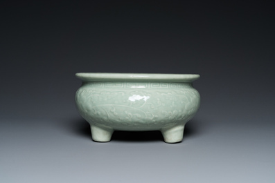 A Chinese celadon-glazed tripod censer with floral scrolls on wooden stand, Qing