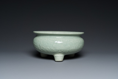A Chinese celadon-glazed tripod censer with floral scrolls on wooden stand, Qing