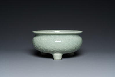 A Chinese celadon-glazed tripod censer with floral scrolls on wooden stand, Qing