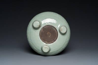 A Chinese celadon-glazed tripod censer with floral scrolls on wooden stand, Qing