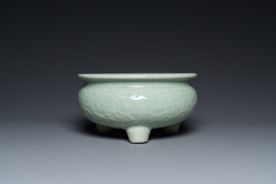 A Chinese celadon-glazed tripod censer with floral scrolls on wooden stand, Qing