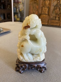 A Chinese celadon and russet jade ram sculpture on wooden stand, 19th C.