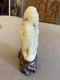 A Chinese celadon and russet jade ram sculpture on wooden stand, 19th C.