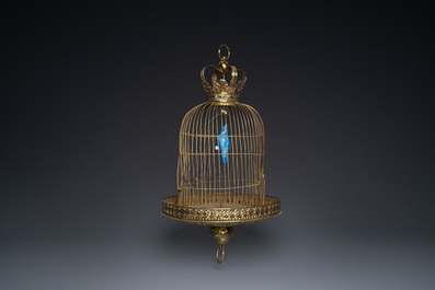 A Dutch or Flemish yellow brass bird cage with a porcelain bird, 18th and 19th C.