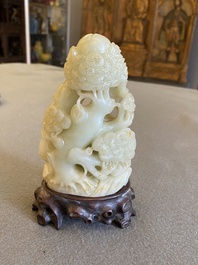 Een Chinese celadon-roest jade sculptuur van een ram op houten sokkel, 19e eeuw