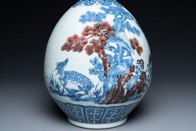 A Chinese blue, white and copper-red bottle vase with a deer and birds among blossoming branches, 19th C.