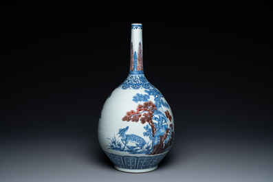 A Chinese blue, white and copper-red bottle vase with a deer and birds among blossoming branches, 19th C.