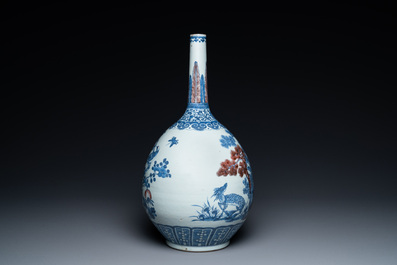 A Chinese blue, white and copper-red bottle vase with a deer and birds among blossoming branches, 19th C.