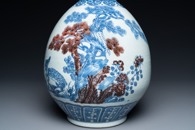 A Chinese blue, white and copper-red bottle vase with a deer and birds among blossoming branches, 19th C.