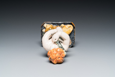 A polychrome Brussels faience sculpture of a putto with a snake standing on a lion, late 18th C.