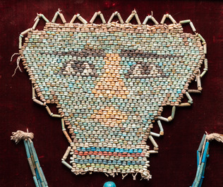 Een Egyptisch dodenmasker in faience parels, een oushabti en een ketting, Ptolema&iuml;sche periode