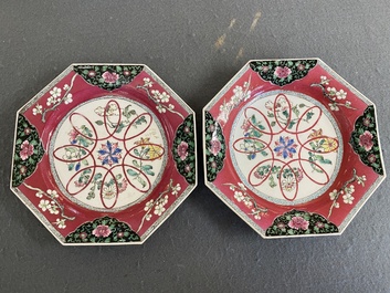 Een paar Chinese octagonale famille rose borden met robijnrode fondkleur, Yongzheng