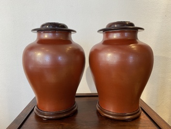 A pair of Chinese monochrome coral-red-glazed vases with wooden stands and lids, Republic
