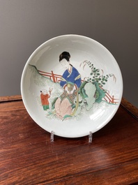 A Chinese famille verte dish with a lady in a garden and a boy offering her a 'jue' vessel, Kangxi