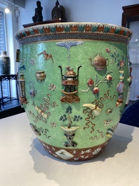 Een Chinese famille rose vissenkom met decor van antiquiteiten op een groene sgraffito fond, 19e eeuw