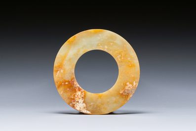 A Chinese celadon and russet jade 'bi' disc, probably Han