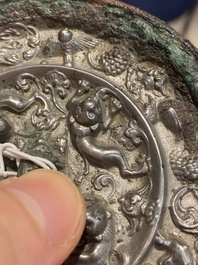 Een Chinese licht verzilverde bronzen spiegel met leeuwen en druivenranken, Tang