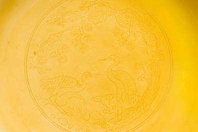 Een paar Chinese monochrome geel geglazuurde schotels met anhua decor van pijnbomen en kraanvogels, Yongzheng merk en periode