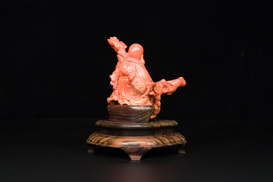 A Chinese red coral figure of a laughing Buddha on wooden stand, 19/20th C.