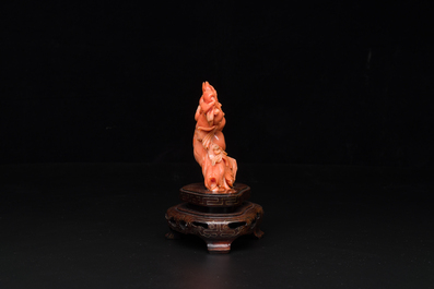 A Chinese red coral figure of a laughing Buddha on wooden stand, 19/20th C.