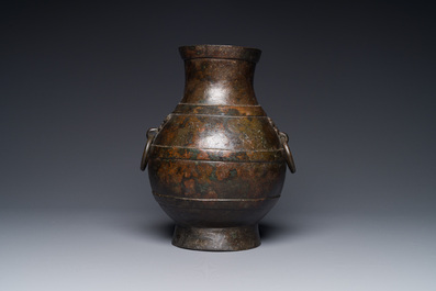 A Chinese bronze 'hu' vase with Han-style taotie handles on wooden stand, Ming