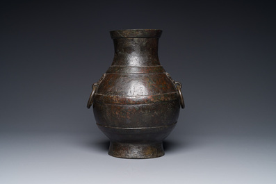 A Chinese bronze 'hu' vase with Han-style taotie handles on wooden stand, Ming