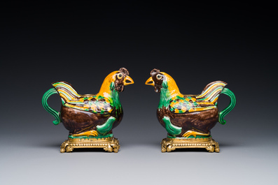 Een paar Chinese sancai geglazuurde kipvormige kannen gemonteerd als kandelaars met verguld brons, Kangxi