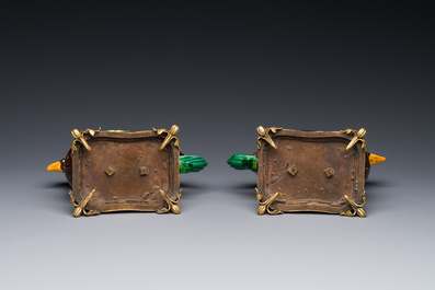 Een paar Chinese sancai geglazuurde kipvormige kannen gemonteerd als kandelaars met verguld brons, Kangxi