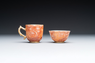 Two rare Chinese iron-red-decorated 'European scene' cups and a saucer, Qianlong