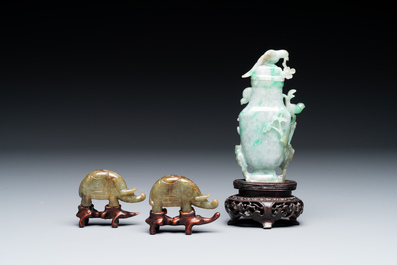A pair of Chinese jade sculptures of elephants and a covered vase on wooden stands, 19th C.