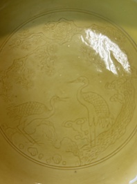 A pair of Chinese monochrome yellow-glazed saucers with incised designs of pine and cranes, Yongzheng mark and of the period