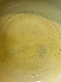 A pair of Chinese monochrome yellow-glazed saucers with incised designs of pine and cranes, Yongzheng mark and of the period