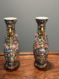 A pair of Chinese Canton famille rose 'mandarin subject' vases with floral relief design, Qianlong