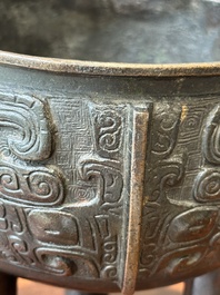 A Chinese archaistic bronze tripod censer on wooden stand, 'ding', Song/Ming