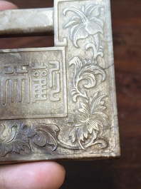 A Chinese white and russet jade lock-shaped plaque with inscription 'Huan Tian Xi Di 歡天喜地', Qing