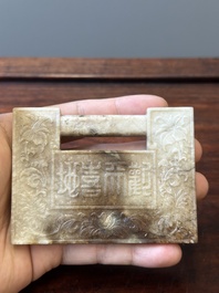 A Chinese white and russet jade lock-shaped plaque with inscription 'Huan Tian Xi Di 歡天喜地', Qing