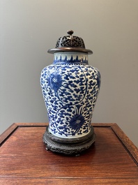 A Chinese blue and white 'lotus scroll' jar with wooden cover and stand, Kangxi