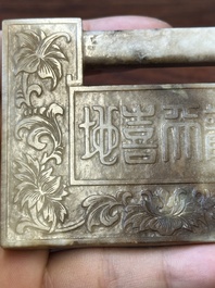 A Chinese white and russet jade lock-shaped plaque with inscription 'Huan Tian Xi Di 歡天喜地', Qing