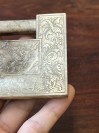 A Chinese white and russet jade lock-shaped plaque with inscription 'Huan Tian Xi Di 歡天喜地', Qing