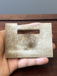 A Chinese white and russet jade lock-shaped plaque with inscription 'Huan Tian Xi Di 歡天喜地', Qing