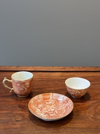 Two rare Chinese iron-red-decorated 'European scene' cups and a saucer, Qianlong