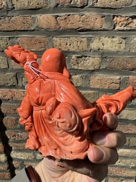 A Chinese red coral figure of a laughing Buddha on wooden stand, 19/20th C.