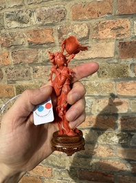 A Chinese red coral figure of a standing lady holding a flower, 19/20th C.