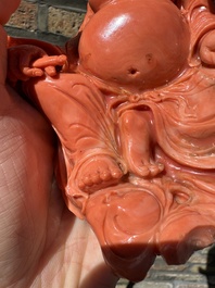 A Chinese red coral figure of a laughing Buddha on wooden stand, 19/20th C.