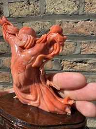 A Chinese red coral figure of a laughing Buddha on wooden stand, 19/20th C.