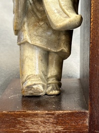 A Chinese partly polychromed soapstone figure on a wooden stand, 18th C.