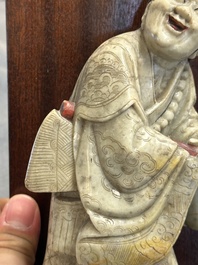 Een Chinese deels gepolychromeerde zeepstenen figuur op houten sokkel, 18e eeuw