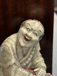 A Chinese partly polychromed soapstone figure on a wooden stand, 18th C.