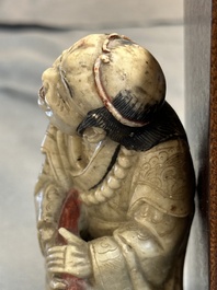 Een Chinese deels gepolychromeerde zeepstenen figuur op houten sokkel, 18e eeuw