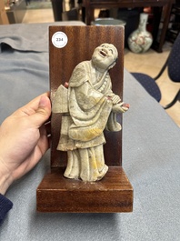 Een Chinese deels gepolychromeerde zeepstenen figuur op houten sokkel, 18e eeuw